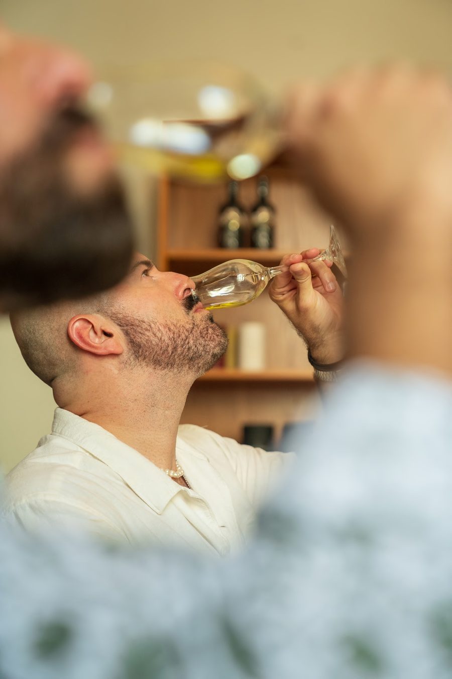 A guest tasting premium olive oil from a blue tasting glass